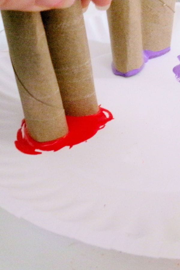 Cardboard tubes dipped in red and purple paint create a beautiful heart stamp bouquet when pressed onto a paper plate.