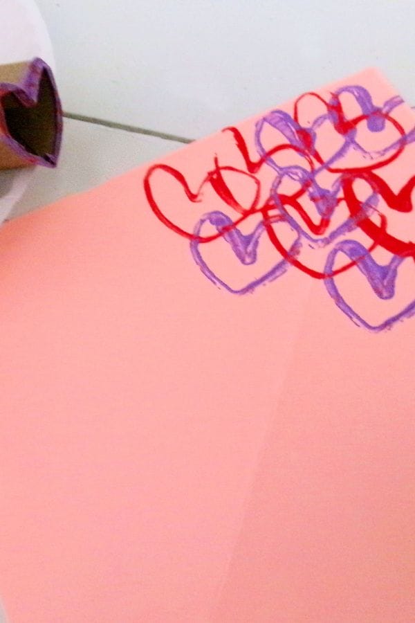 A delicate paper adorned with red and purple heart stamps lies elegantly next to a crafted heart-shaped stamp, forming a charming heart stamp bouquet.
