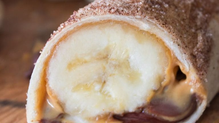 The Peanut Butter Banana Roll Up is a delightful treat featuring a banana wrapped in a tortilla with creamy peanut butter and luscious chocolate, all sprinkled with cinnamon sugar for an irresistible finish.