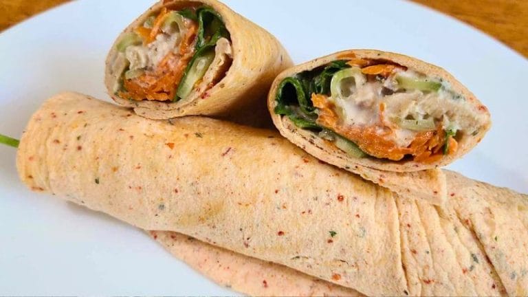 Close-up of a sliced wrap on a plate, filled with tuna, crisp vegetables, and a creamy dressing, all elegantly presented as a tortilla-free delight.