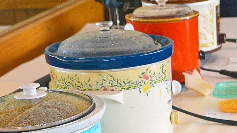 A row of slow cookers with steam on the lids, each in different colors and patterns, adorns the table, ready to turn Crockpot recipes into meals even picky eaters will love.