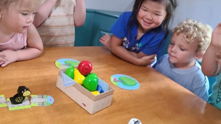 Children sit around a table, enthusiastically engaged in a game featuring colorful balls and charming animal-themed pieces, cleverly woven into lesson plans on French culture.