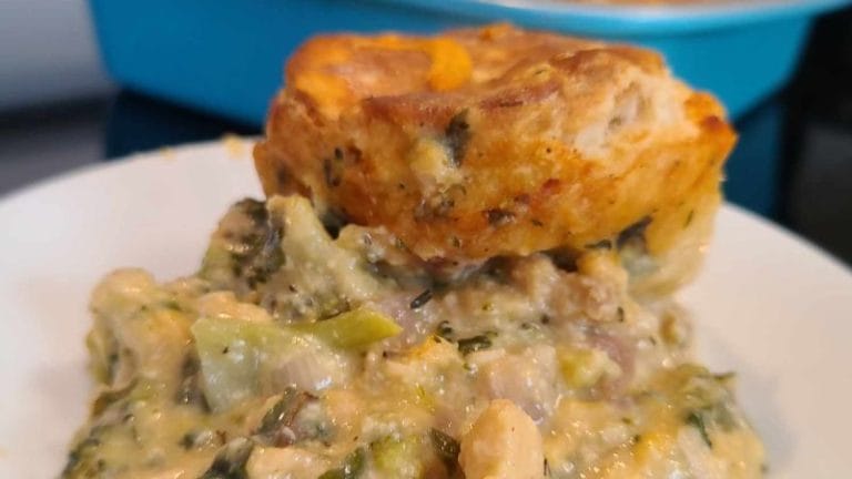 A savory muffin crowns a creamy tuna biscuit casserole, brimming with broccoli, cheese, and herbs, elegantly served on a plate.
