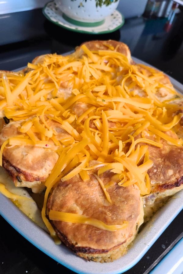 A delicious Tuna Biscuit Casserole, featuring flaky golden biscuits and a sprinkle of shredded cheddar cheese, all baked to perfection in a rectangular pan.