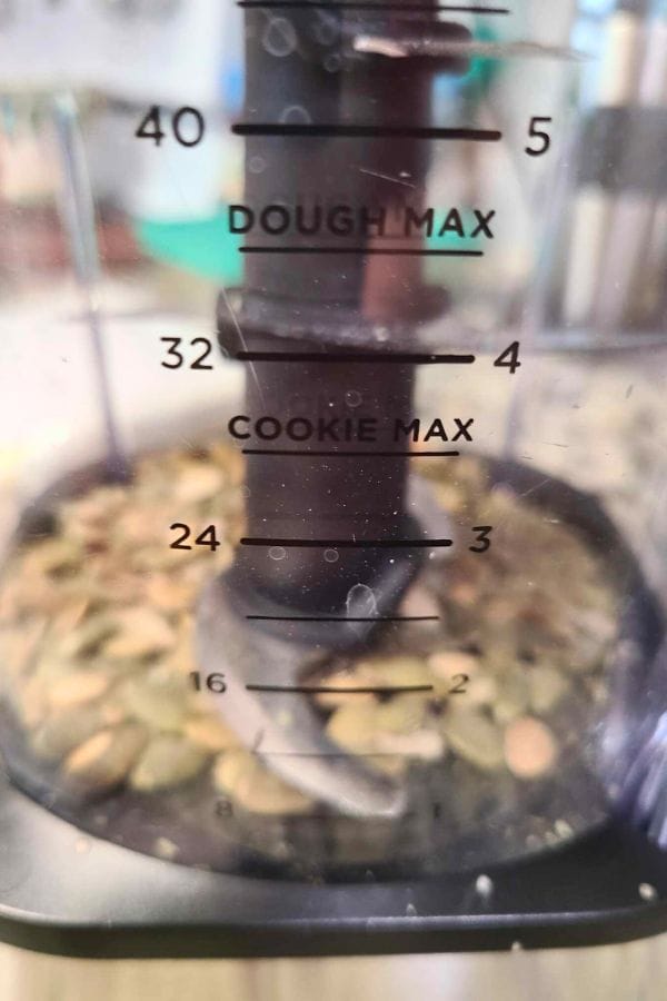 Inside view of a food processor bowl with seeds at the bottom, ready to mix ingredients for easy tuna croquettes. The bowl has marked measurements labeled "DOUGH MAX" and "COOKIE MAX" in cups and milliliters.