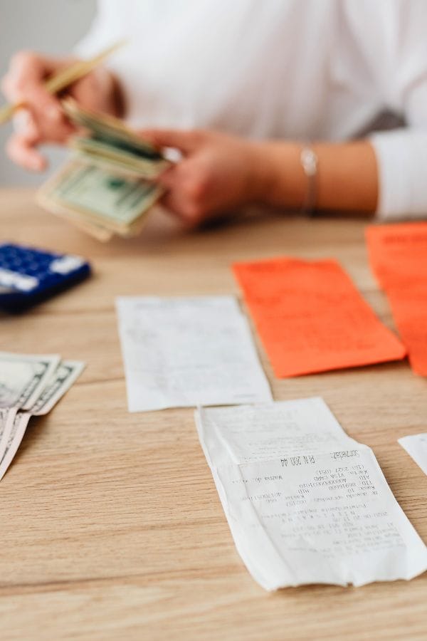 Amidst scattered receipts and a calculator, a person counts cash at the table, almost like piecing together a plan for success. Much like mastering how to advertise a daycare, this task requires strategy and attention to detail.