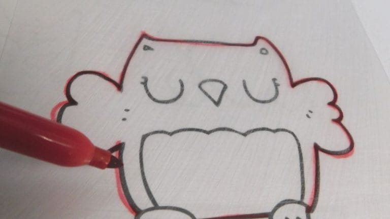 A red marker, one of the best markers for Shrinky Dinks, outlines a cartoon owl drawing on a white surface.