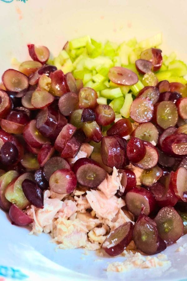 Chopped grapes, celery, and shredded chicken in a bowl come together harmoniously like the ingredients of a Ranch Tuna Pasta Salad.