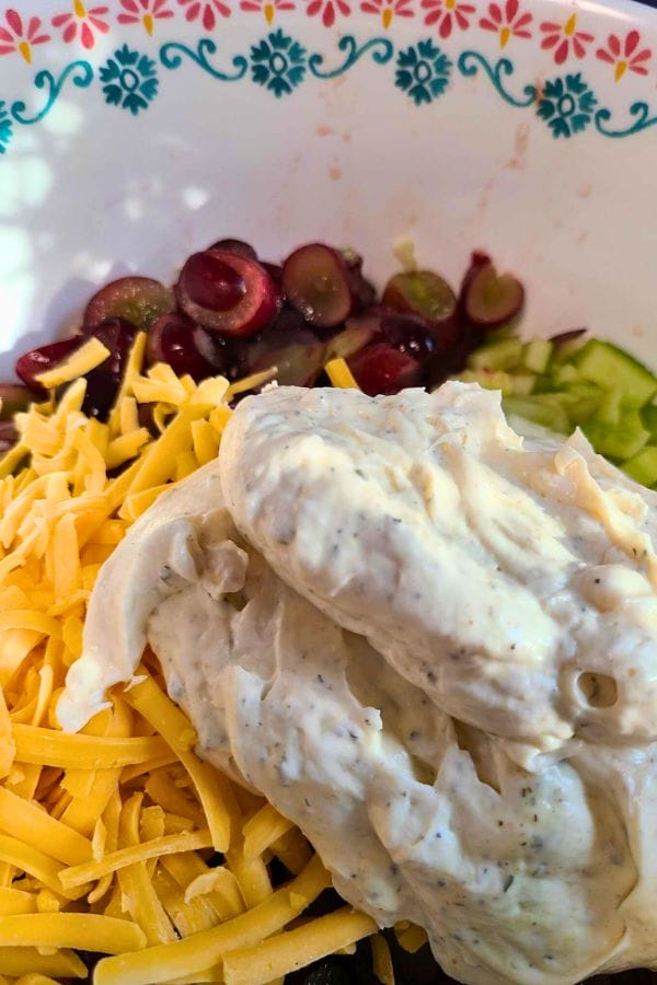 Bowl with shredded cheese, sliced grapes, chopped cucumber, a dollop of creamy dressing, and the bold flavors of Ranch Tuna Pasta Salad.