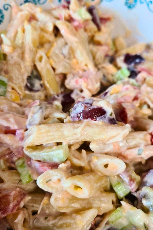 Close-up of a Ranch Tuna Pasta Salad with penne, diced vegetables, grapes, and a creamy dressing in a decorative bowl.