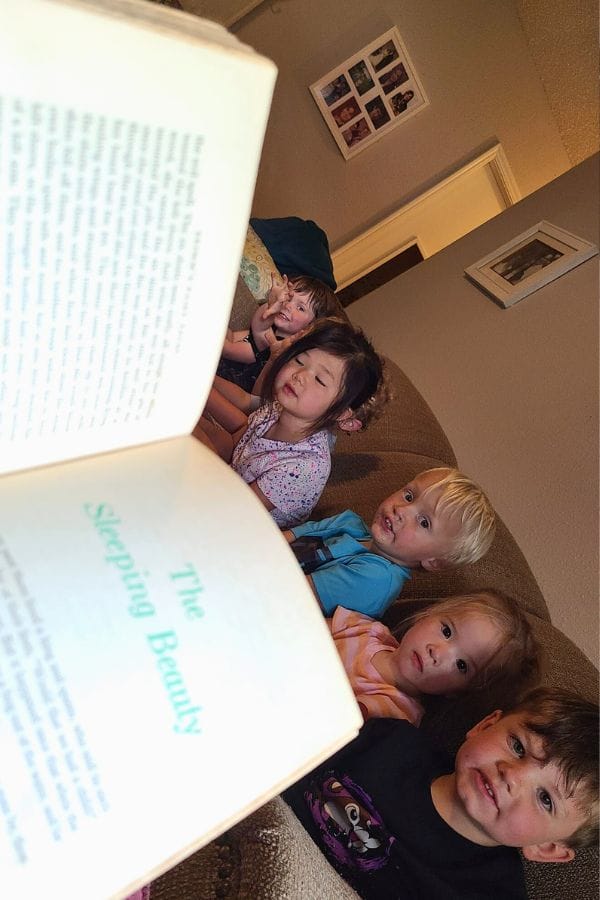 Five children sit on a couch, captivated by a story from "The Sleeping Beauty." The tale unfolds like a cherished heirloom of German culture, where timeless traditions and enchanting narratives weave together to spark their imaginations.