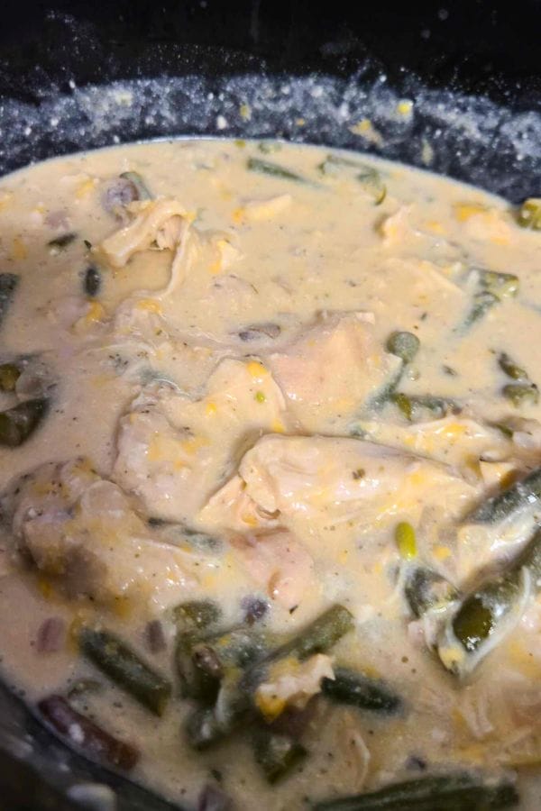 A pot of creamy soup with chunks of chicken, green beans, corn, and diced onions offers a taste reminiscent of a classic Green Bean Chicken Casserole.