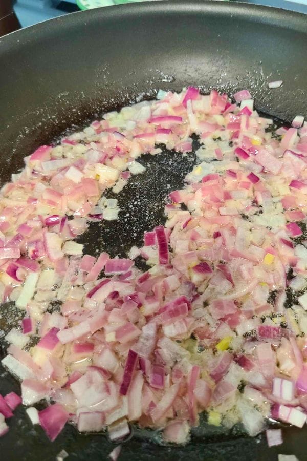 Chopped red onions sizzle gently in a pan with oil, setting the stage for a comforting Cream of Anything Soup.