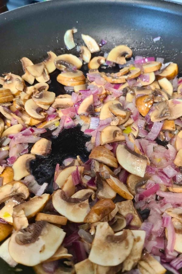 Sliced mushrooms and chopped red onions sizzle in a non-stick pan, forming the perfect base for a hearty Cream of Anything Soup.