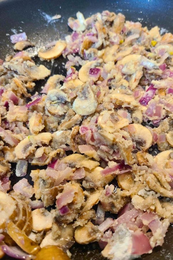 Chopped onions and mushrooms sauté in a frying pan, creating the perfect base for a savory Cream of Anything Soup.