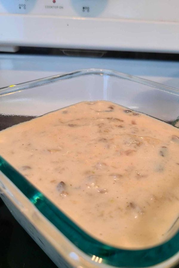 Close-up of a glass dish on the stovetop, brimming with creamy mushroom soup and enticingly visible mushroom pieces—this could be the heartwarming start to your favorite cream of anything soup adventure.