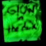 A glowing green square with the handwritten words "GLOW in the dark" visible in dark letters, resembling a Glow in the Dark Sensory Bag.