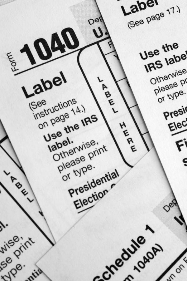 Close-up of overlapping U.S. IRS tax forms, including Form 1040 and labeling instructions, in black and white—ideal for understanding home daycare taxes.