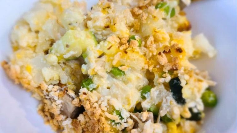 A close-up of a mixed rice dish with visible peas, scrambled eggs, vegetables, and a crunchy topping served in a white bowl—reminiscent of a Tuna Casserole Without Noodles.