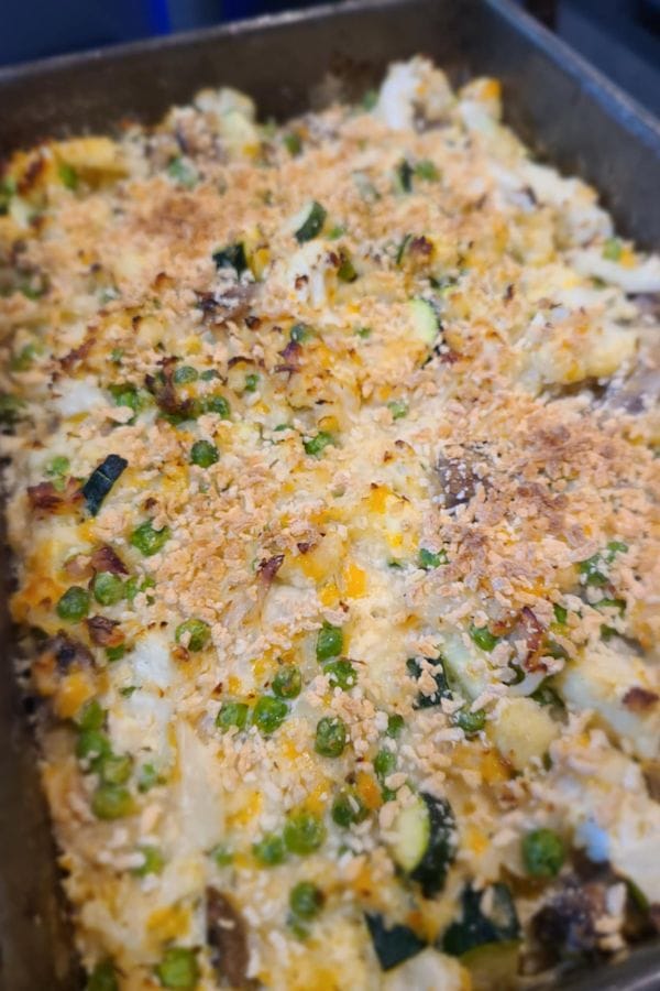 A baked casserole topped with breadcrumbs, featuring mixed vegetables such as peas, zucchini, cauliflower, and cheese in a rectangular pan—a delicious Tuna Casserole Without Noodles option.