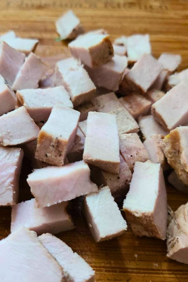 Small cubes of cooked, diced meat arranged on a wooden cutting board—perfect for adding to Leftover Pork Chop Soup.