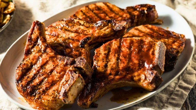 Grilled pork chops with barbecue sauce arranged on a white plate—perfect inspiration for delicious leftover pork chop recipes.