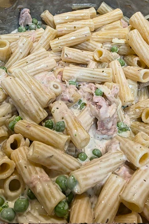 Pasta with green peas, pieces of ham, and a creamy white sauce mixed together for a dish reminiscent of Tuna Alfredo Bake.