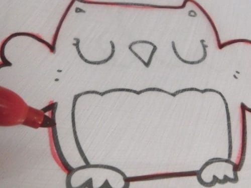 A red marker traces the outline of a simple owl drawing on white paper, perfect for creating Winter Shrinky Dink Patterns.