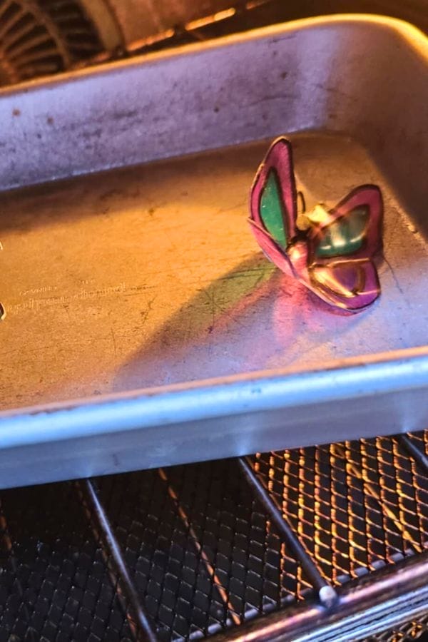 A metal butterfly decoration sits inside an empty baking pan on an oven rack, adding whimsical charm reminiscent of Spring Shrinky Dink Patterns.