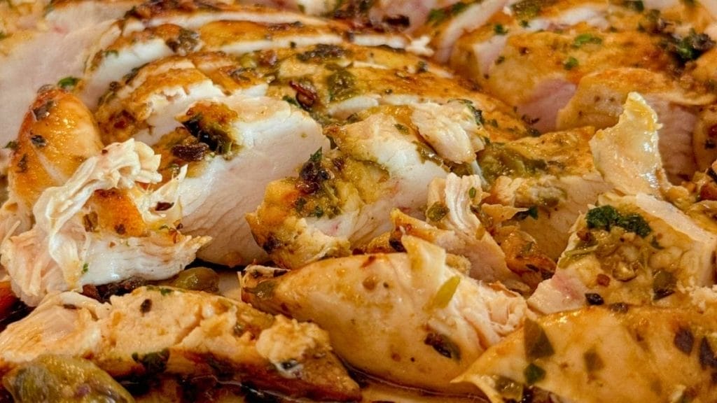 Close-up of sliced, seasoned cooked chicken breast with herbs and spices—perfect for inspiring creative leftover chicken ideas.