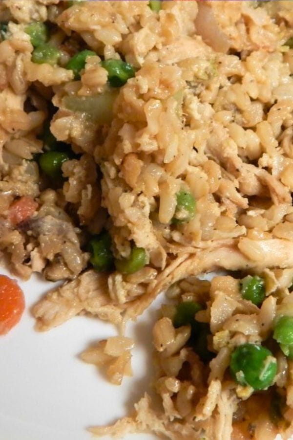 A close-up of a plate with a serving of rice, shredded chicken, peas, and mixed vegetables—perfect for those looking for delicious Leftover Chicken Ideas.
